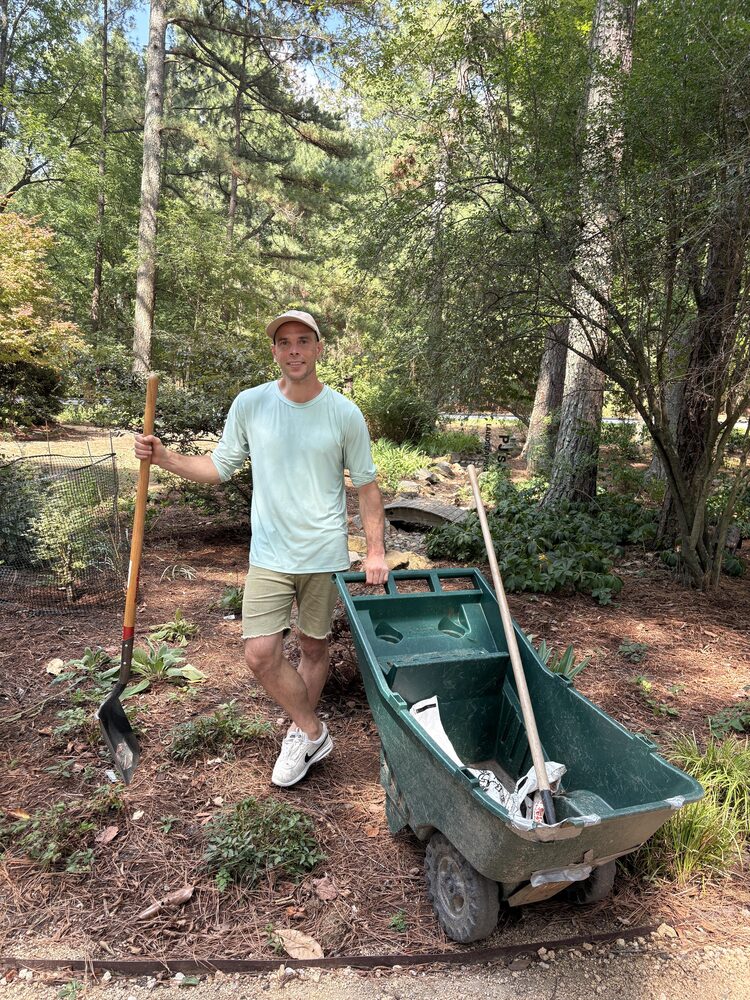 Peter, owner of Peter James Landscaping, standing with a shovel and cart